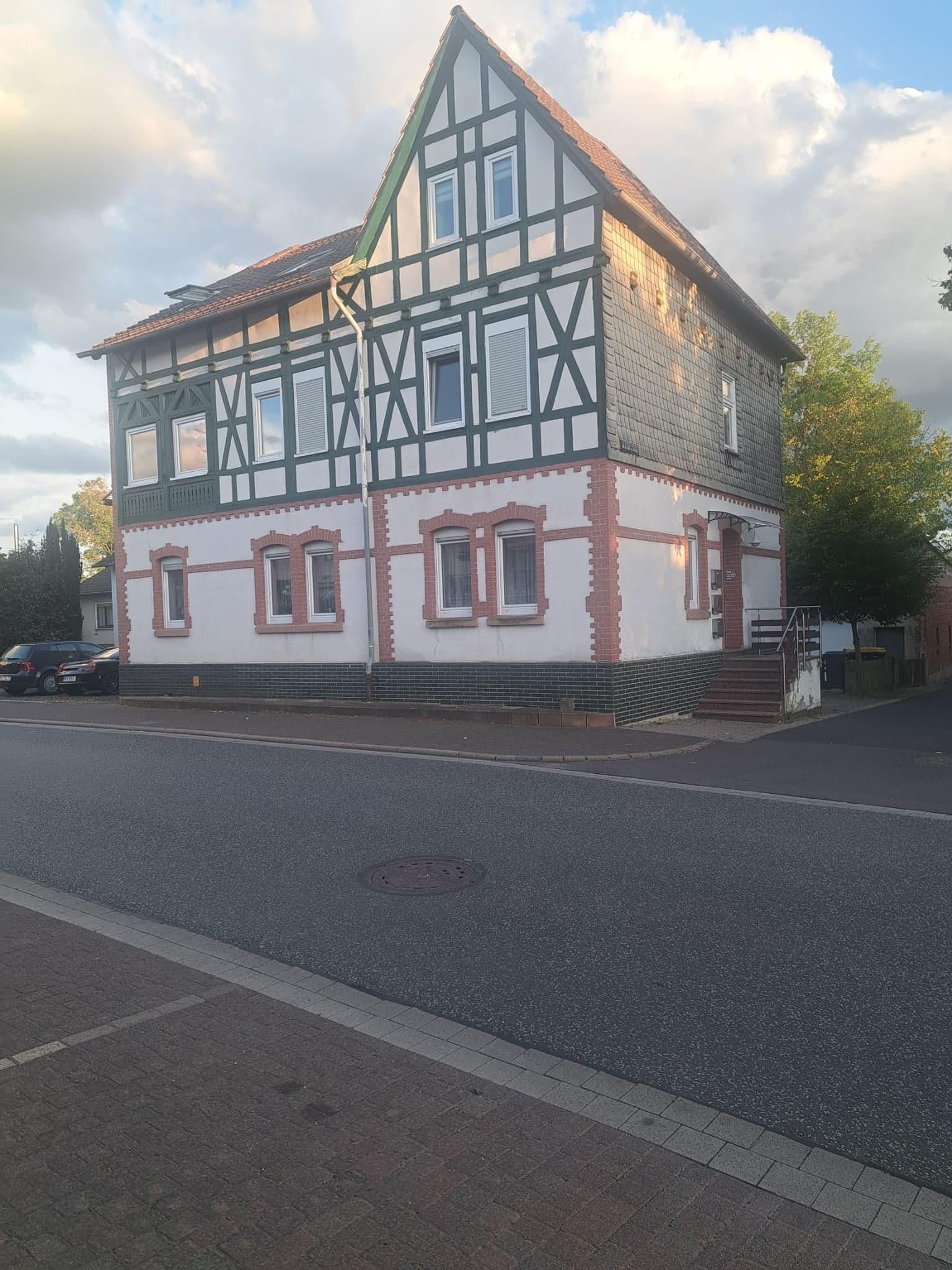 Fachwerkhaus der Wohnung A von der Straße aus gesehen, mit Parkplatz davor