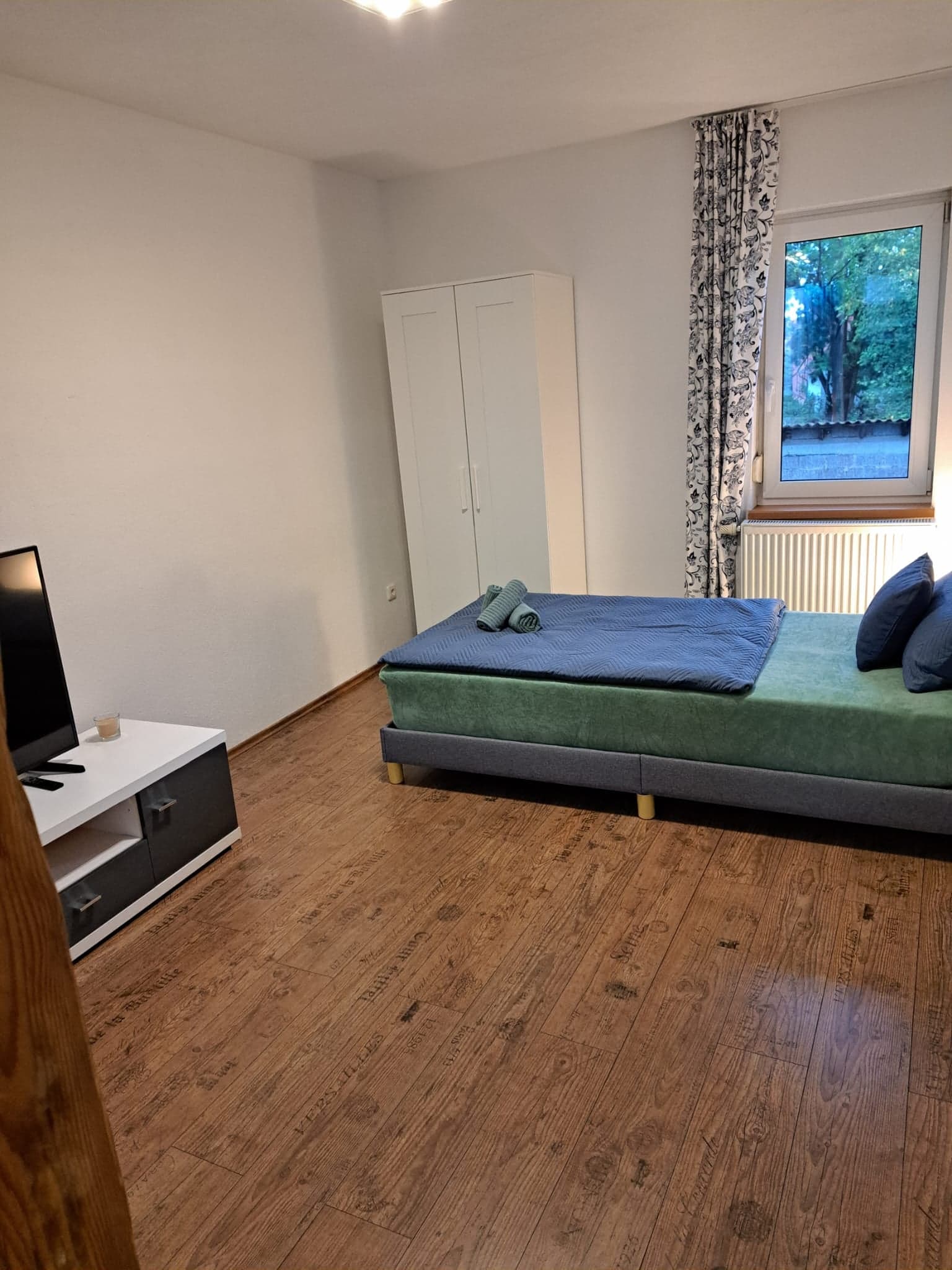 Zimmer der Wohnung A mit Bett, Flachbildfernseher auf dem Lowboard und Kleiderschrank