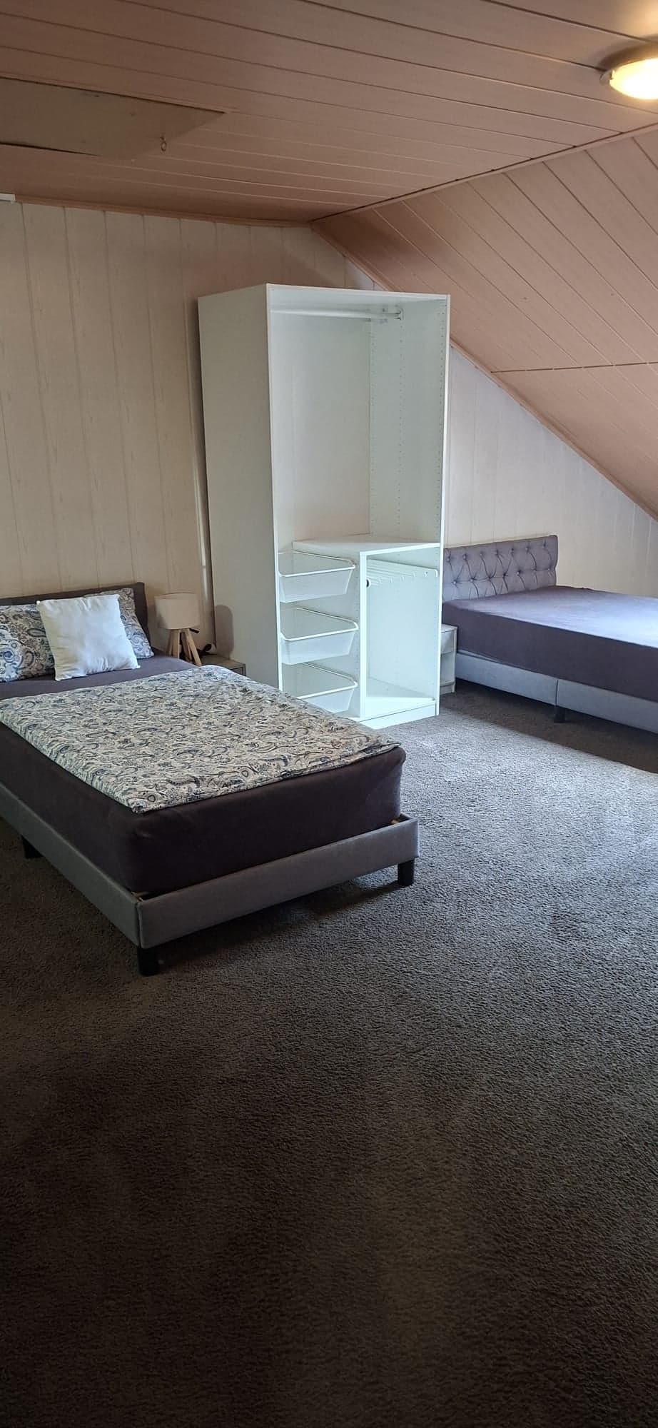 Zimmer der Wohnung B mit zwei Einzelbetten, offenem Kleiderschrank und Teppichboden