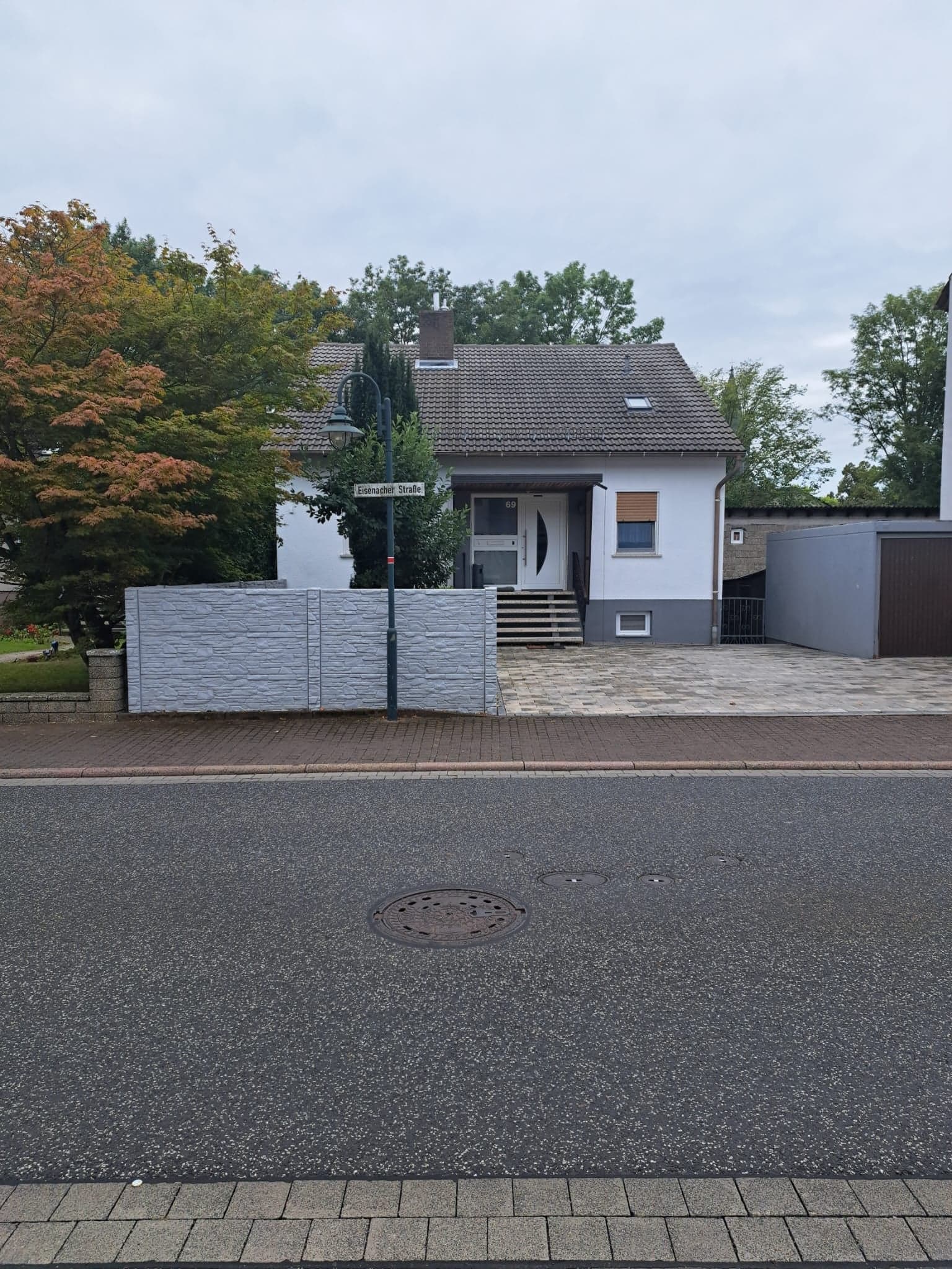 Das Haus der Wohnungen B und C von der Eisenacher Straße aus, mit gepflastertem Parkplatz