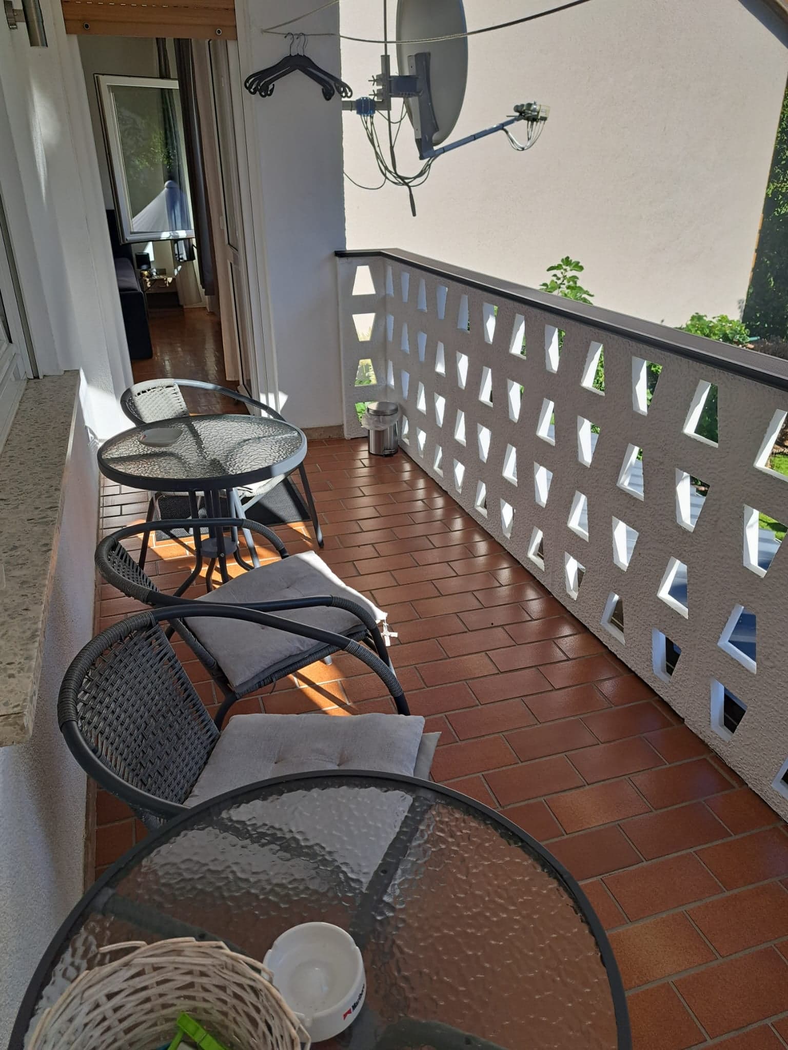Überdachter Balkon der Wohnung C mit Korbsesseln, Beistelltischen und Blick ins Grüne