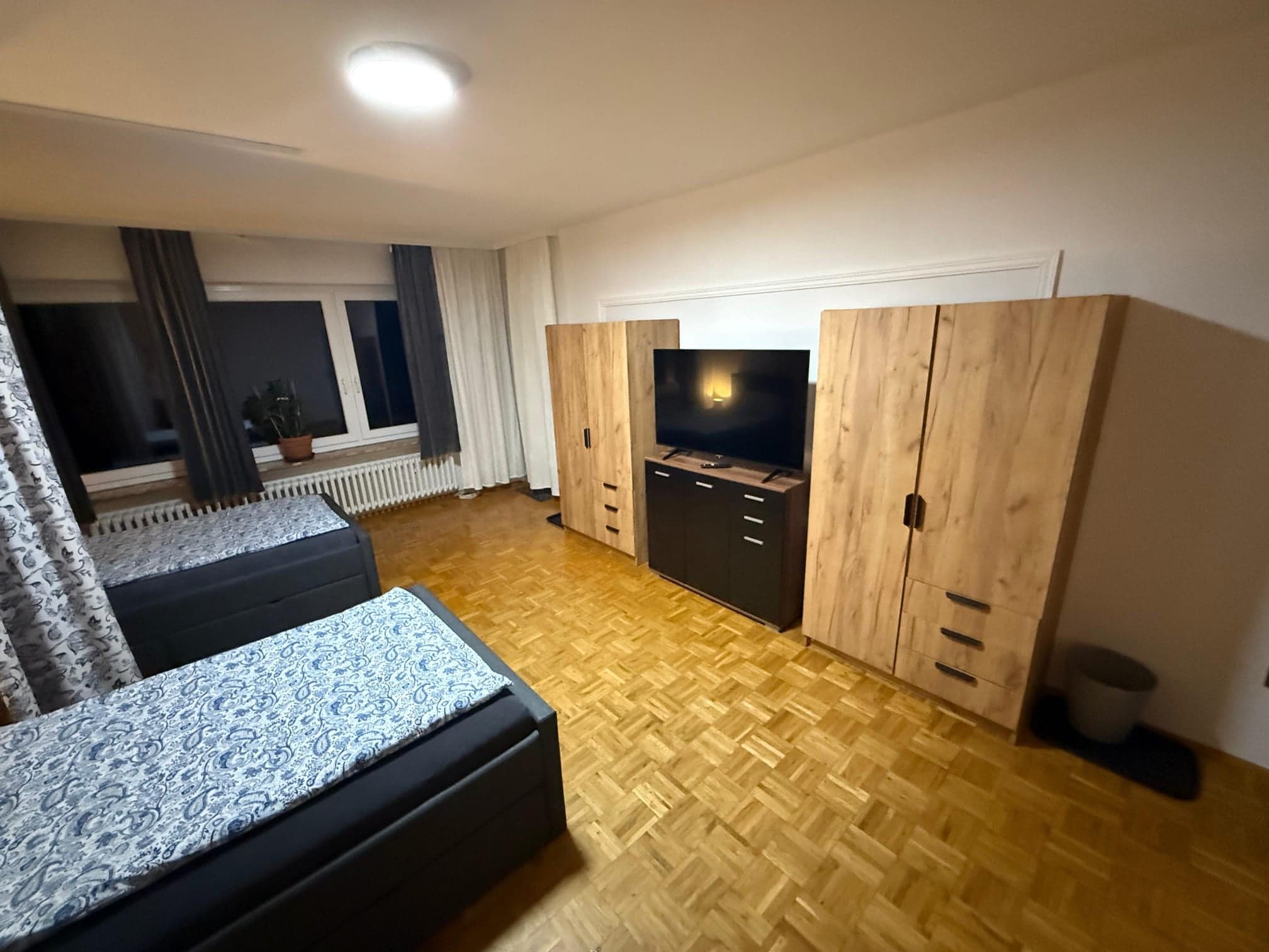 Zimmer der Wohnung C mit zwei Einzelbetten, großem Fernseher und zwei Kleiderschränken