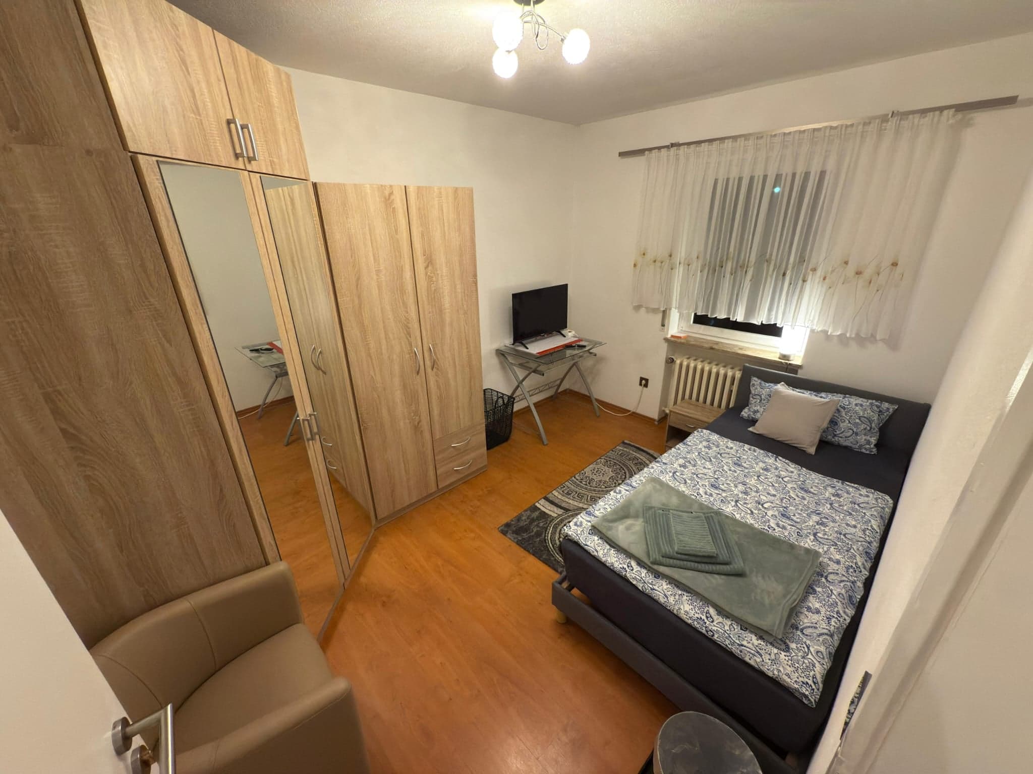 Einzelzimmer der Wohnung C mit Bett, Schreibtisch und Kleiderschrank mit Spiegeltür
